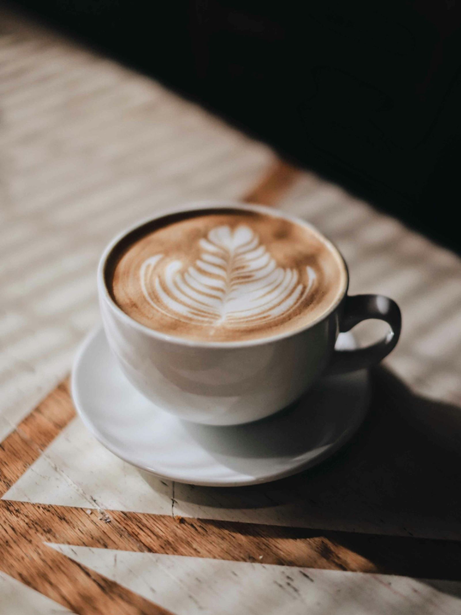 A latte on a wooden counter in morning light